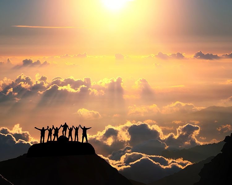 On the top of the world together. A group of people stands on a On the top of the world together. A group of people stands on a hill over the beautiful cloudscape.